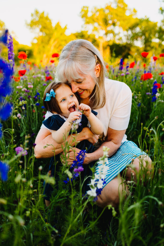 grandmother and granddaughter hugging in a field of wildflowers. spring mini session ideas