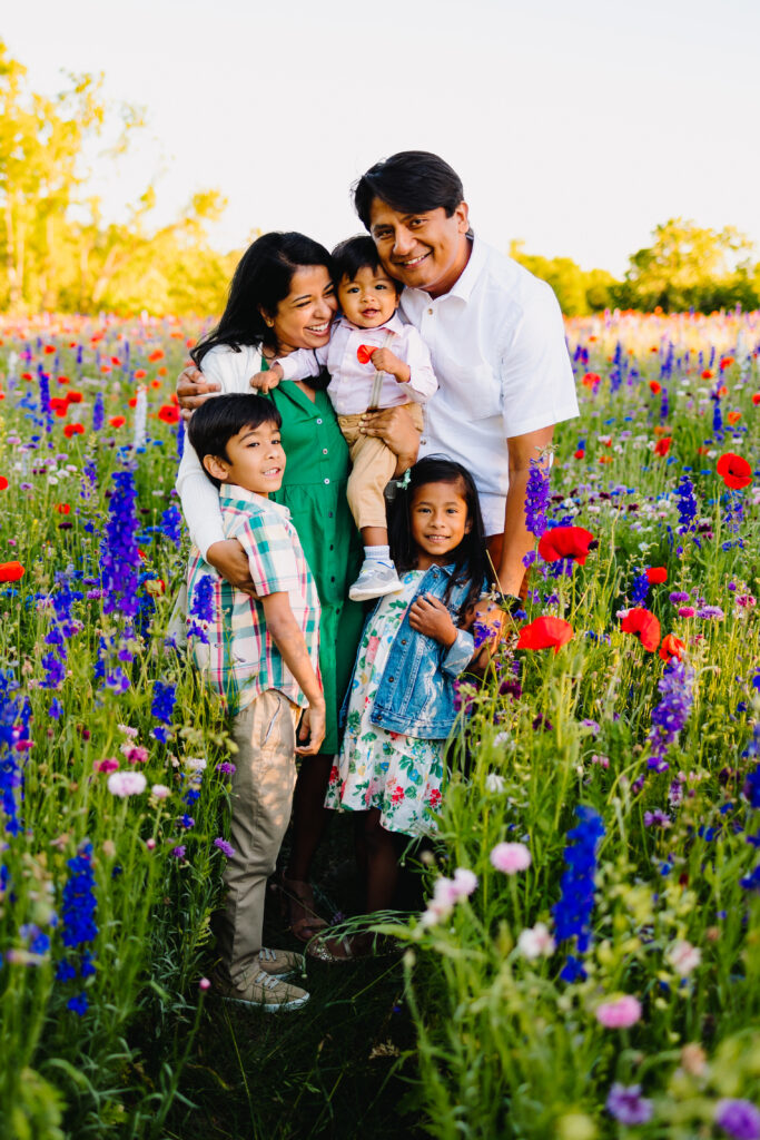 family of 5 standing in a wildflower field in dallas and laughing