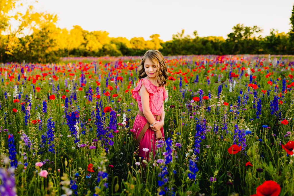 young girl standing in a field of wildflowers during a mini session with wandermama photography. mini session inspiration