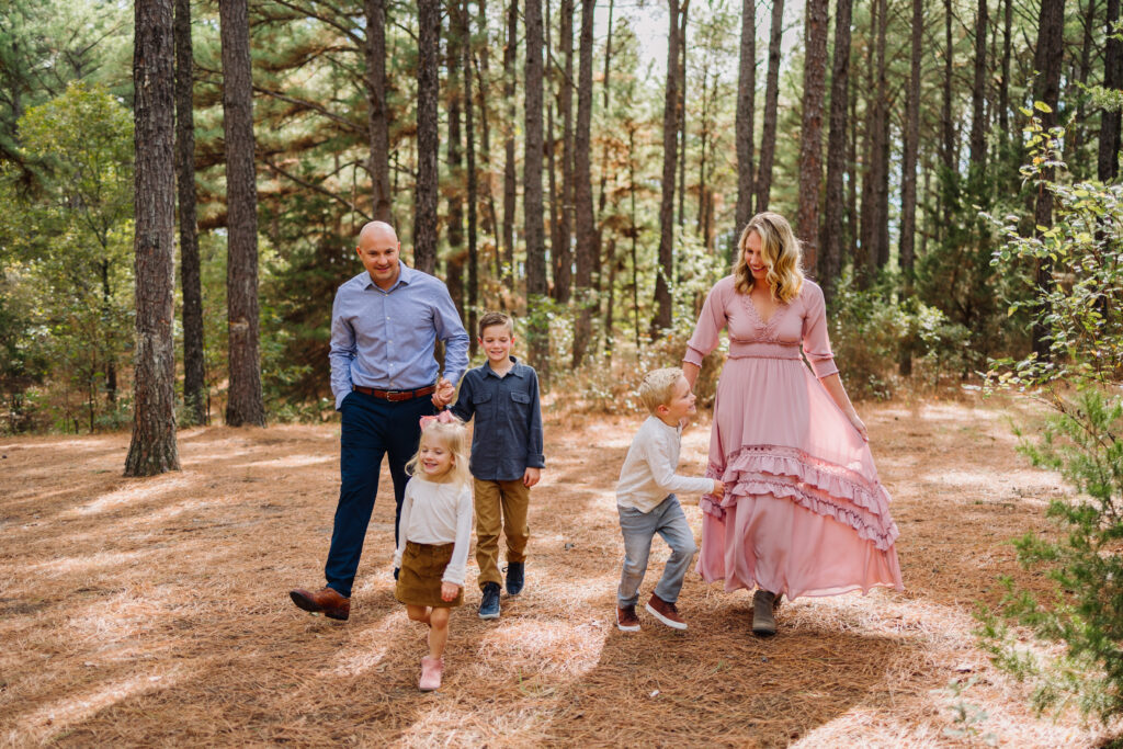 a family with 3 kids walks through a pine forest near dallas, texas during their fall family mini session